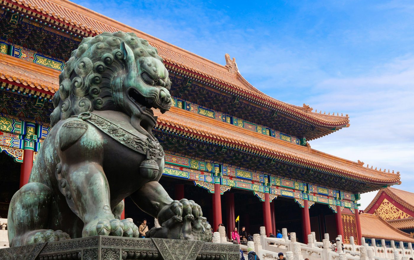 Bronze guardian lion statue at the Forbidden City with ornate imperial palace architecture — Beijing, China