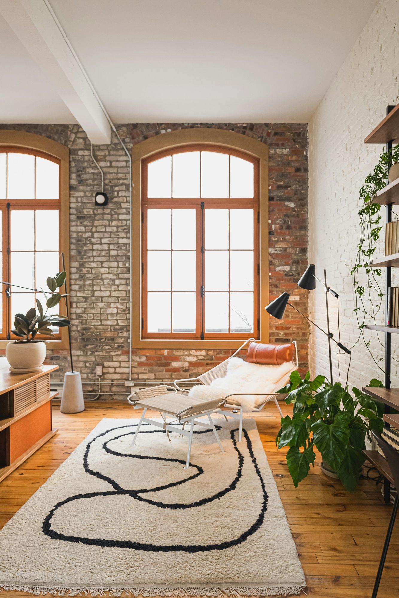 A custom hand-knotted rug with a flowing black line motif anchoring a sunlit loft living room