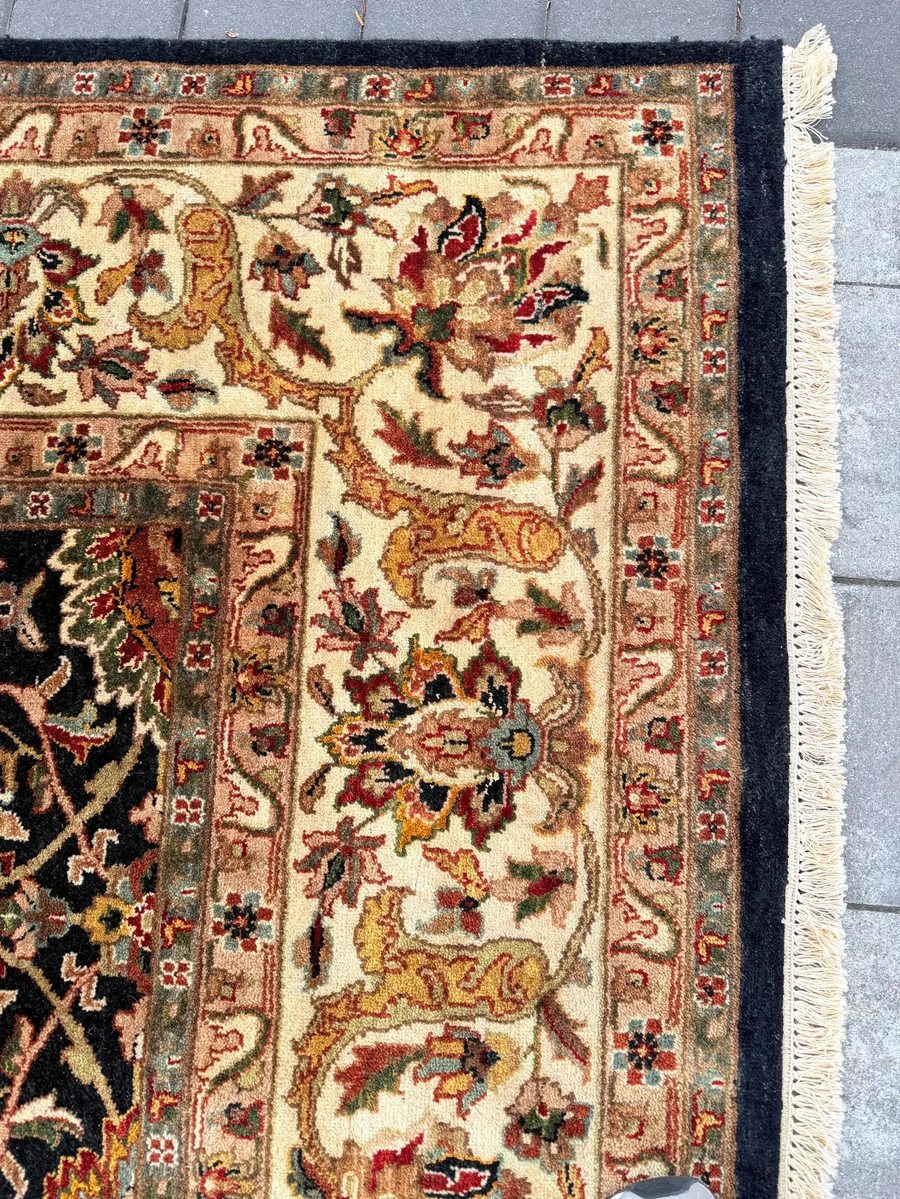Indo-Persian rug — black field with ivory border and multicoloured floral arabesque
