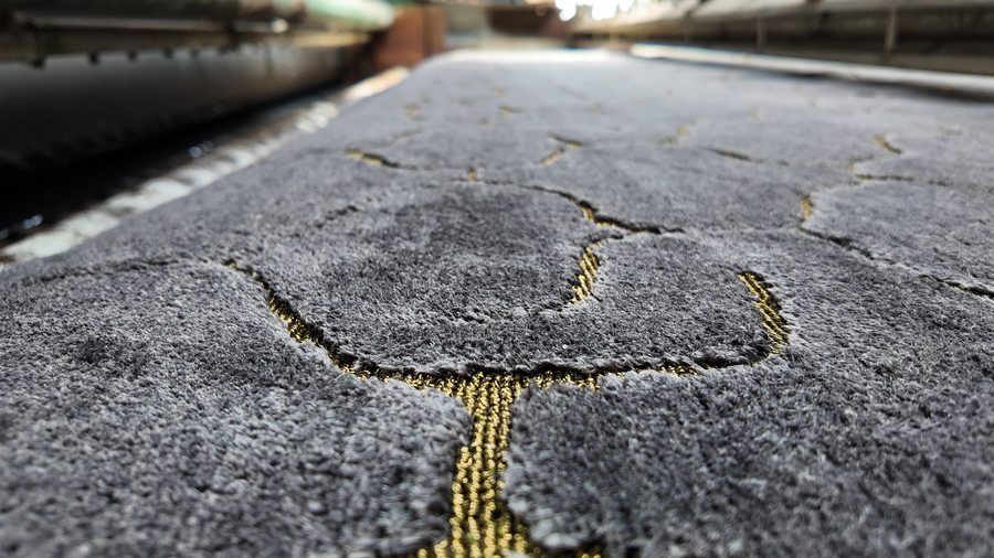 Contemporary Nepali rug in charcoal wool with gold tinsel accents showing carved pile texture