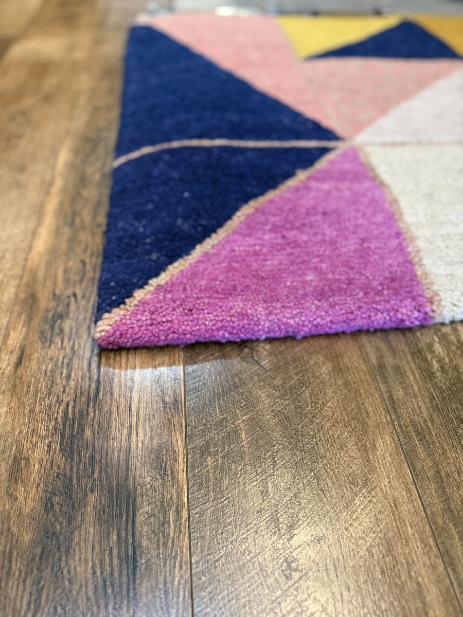 Kush Up custom Nepali rug corner detail showing bold geometric triangles in navy pink purple and ivory