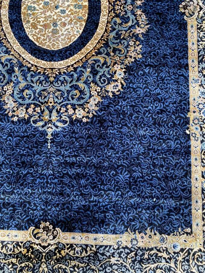 A deep blue Persian rug with a central floral medallion and gold detailing