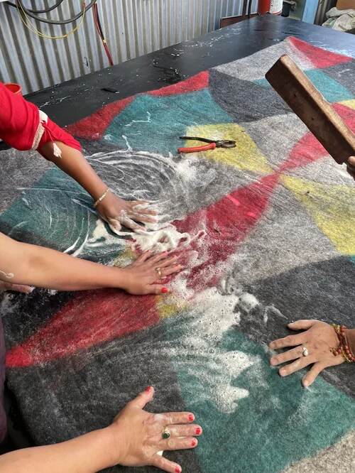 Artisans felting a colorful wool rug by hand at Peace Industry