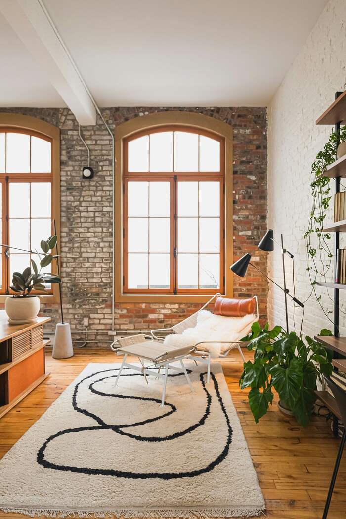 A cream and black line-drawing rug in a sunlit loft