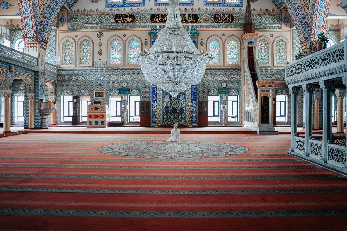 Interior of a grand mosque in Turkmenistan — ornate tilework and red carpet