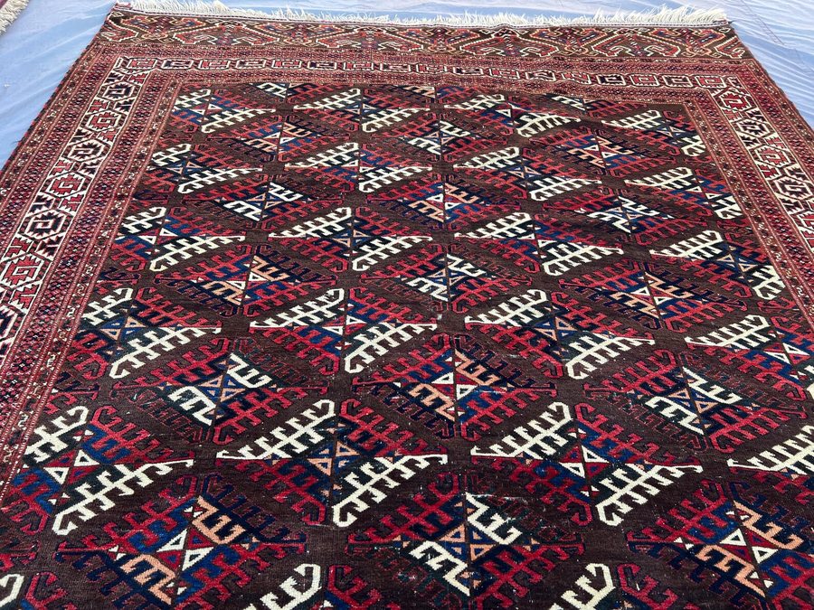 Yomut main carpet — dark brown field with hooked dyrnak guls